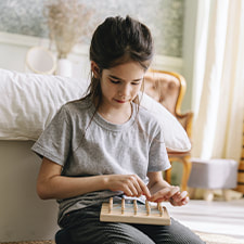 Photo of a child playing alone with a wooden toy. This represents how ADHD and autism evaluations can provide a valuable roadmap for growth and improvement.