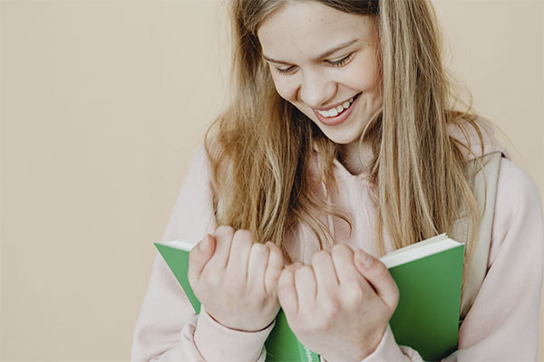 Photo of a young woman reading a book and smiling. This represents how you can find relief by better understanding yourself through an expert assessment. Central Texas Neuropsychology, LLC provides neuropsychological and psychological evaluations in Texas and online.